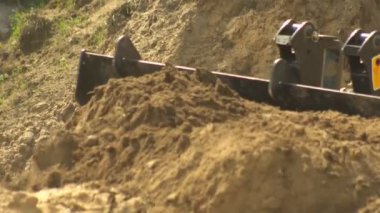 Traktör yükleyicisi yol, arka plan, endüstri, 4k, çok fonksiyonlu inşaat sırasında büyük bir kovada toprak topluyor.