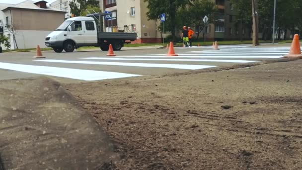 Pracovníci aplikovat barvou vodorovné značení silnice zebra pro pěší přechod na křižovatce v městské ulici asfalt — Stock video