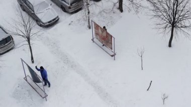 İki adam kış havasında evdeki halıları söküp temizliyor..
