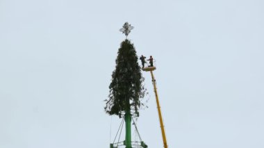 İşçiler, Yeni Yıl tatili ve kutlamalarından sonra şehrin merkez meydanında bir Noel ağacı yapısını söküyorlar. Bölüm 3. Kışın hava çalışma platformu. Elle tutulur orta atış