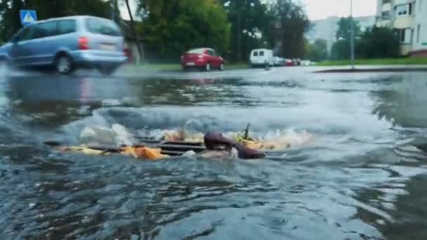 L'acqua dalla strada sfocia nel collettore fognario con griglia durante la pioggia. Canale principale della rete di drenaggio. Tempo piovoso in città. Condizioni cattive e pericolose per il traffico — Video Stock