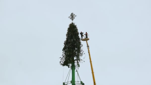 Os funcionários desmontam uma estrutura de árvore de Natal na praça central principal da cidade depois de férias de Ano Novo e celebrações. Parte 3. Plataforma de trabalho aéreo no inverno. Mão no meio do tiro — Vídeo de Stock