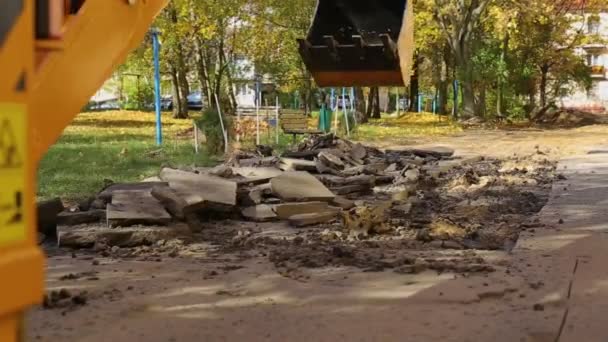 Un cucharón trasero excavadoras cava en el patio de un edificio residencial. Sustitución de la calefacción principal y tuberías para el agua, industria — Vídeo de stock