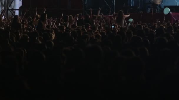 Kerumunan orang melambaikan tangan selama konser musik rock di malam hari. Suara pop. Penampilan artis band alternatif di panggung beriluminasi. Kehidupan malam. Pemirsa menyukai acara ini — Stok Video