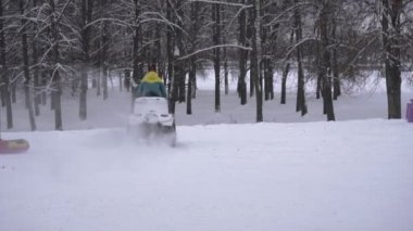 Biri kışın nehir kıyısındaki karlı bir sahilde arazi aracına biniyor. Kar maskeli ve gözlüklü bir adam Atv yarışları sırasında Dörtlü bisiklette ağır çekimde hareket ediyor.
