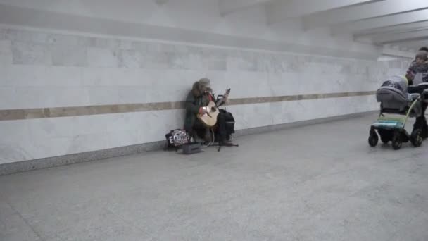 Las personas mayores sin hogar ganan dinero tocando un instrumento musical en el paso subterráneo en MINSK, BELARUS 12.21.18. Disparo de mano en movimiento — Vídeo de stock