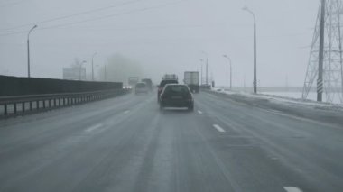 Kar fırtınası sırasında araba piste çıkıyor. Ön camdan içeriden taksiyi izle. Kış zamanı kar yağışı. Trafik için kötü hava koşulları. Seyahatler için tehlike. Zemin yolundaki camsı kara buz