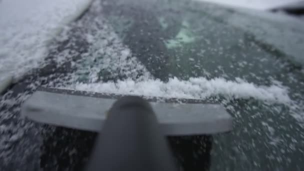 冬は雪や氷から車のフロントガラスやフロントガラスをきれいにします。スクレーパーやスクラバーの閉鎖。悪天候と寒さ。一人称視点。庭の駐車場で昼間のスローモーション. — ストック動画