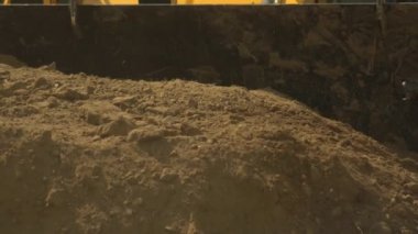 Traktör yükleyicisi inşaat sırasında büyük bir kovada toprak kazanıyor, yakın plan. İnşaat ve yol mühendisliği, endüstri, geçmiş