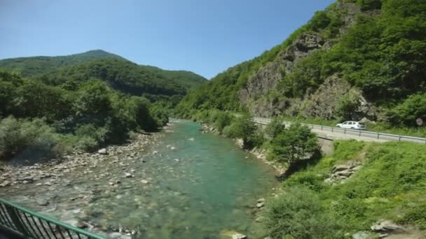 Горная река Тара в Черногории. Туристический ручной съемки природного ландшафта через окно автобуса в движении. По пути к Биоградскому озеру, проход через реку. Ясное небо без облаков — стоковое видео