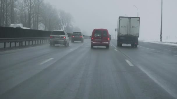 Car rides on highway during bad weather. View from inside cab through windshield glass. MINSK, BELARUS 12.21.18. Winter daytime. Traffic, snowfall. Danger for trips. Handheld shot. Blizzard — Stock Footage Car rides on highway during bad weather. View from inside cab through windshield glass. MINSK, BELARUS 12.21.18. Winter daytime. Traffic, snowfall. Danger for trips. Handheld shot. Blizzard Stock Video