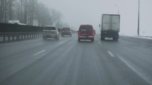 Kötü havada otoyolda araba sürüyor. Ön camdan içeriden taksiyi izle. Minsk, Belarus 12.21.18. Kış gündüz vakti. Trafik, kar yağışı. Seyahatler için tehlike. El kamerasıyla. Kar Fırtınası — Stok video