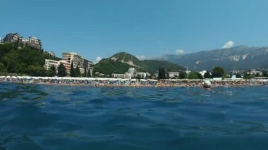 Budva yakınlarındaki Becici kasabasının sahil şeridi manzarası. Tatil köyü plajı. Karadağ, Mavi Deniz. Arka planda oteller ve dağlar