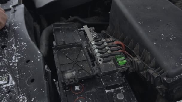 Uomo installa carica batteria automobilistica in auto dopo riparazione o riparazione. Malfunzionamento o problema con l'automobile. Cappuccio o cuffia sollevati durante il giorno d'inverno nel parcheggio. Primo piano della batteria al piombo-acido. Rallentatore — Video Stock