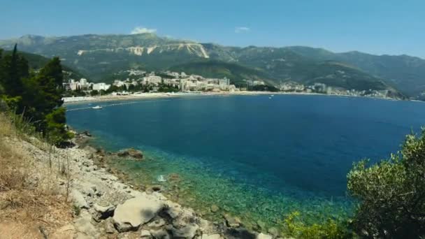 Budva yakınlarındaki Becici kasabasının sahil şeridi manzarası. Karadağ, tatil köyü plajı. Mavi deniz. Arka planda oteller ve dağlar — Stok video