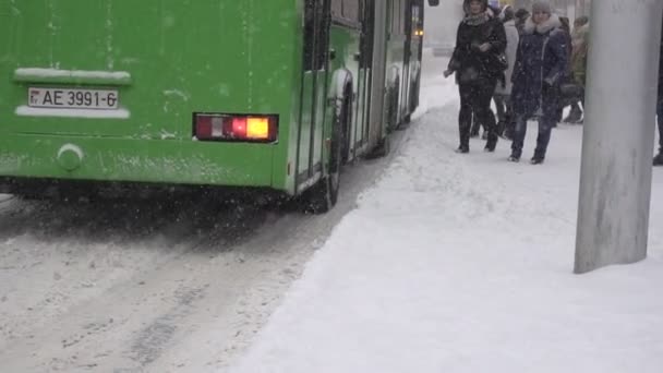 BOBRUISK, BELARUS - JANEIRO 14, 2019: As pessoas vêm para o ônibus na parada de ônibus no inverno na cidade, queda de neve, slow mo — Vídeo de Stock