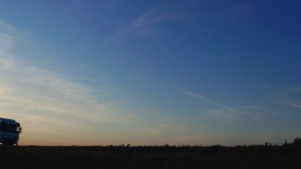 Um grande caminhão vagão transporta carga em um semi-reboque contra um céu azul à noite. Conceito de logística e frete, espaço de cópia — Vídeo de Stock