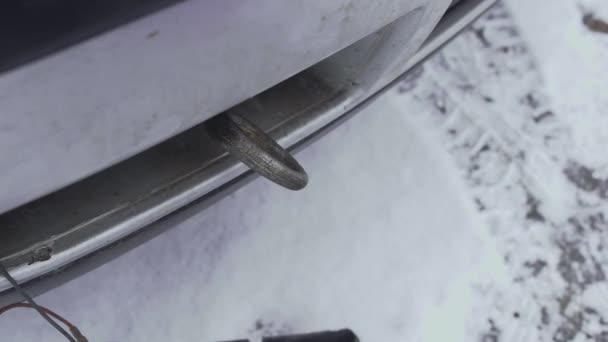Το ένα αποδίδει ένα εύκαμπτο σχοινί γερανό carabiner σε ένα πλαίσιο με ρυμούλκηση ή ράβδο του αυτοκινήτου. Κοντινό πλάνο. Χειμερινή μέρα στο πάρκινγκ της αυλής. Δυσλειτουργία ή πρόβλημα με την αυτόματη. Κακός και κρύος καιρός — Αρχείο Βίντεο