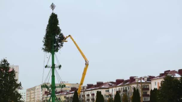 Les travailleurs démontent une structure d'arbre de Noël sur la place centrale principale de la ville après les vacances et les célébrations du Nouvel An. Première partie. Plateforme de travail aérien en hiver. Plan large tenu à la main . — Video