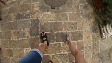 Erkek ve dişi bacakları dar kaldırımlarda yürüyor. Turist gezisi, seyahat. Fisheye merceği. Taş yol. Romantik ruh hali, tatil