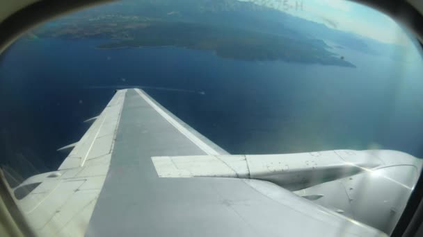 Самолеты летают над морем и землей возле аэропорта Тиват. Вид через окно иллюминатора на крыло пассажирского самолета. Туризм в Черногории — стоковое видео