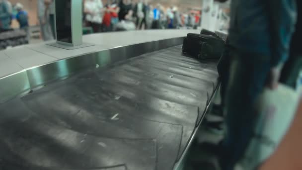 Pasajeros esperando su equipaje cerca de la cinta transportadora en el aeropuerto. Turistas después de que el vuelo llegó al aeródromo. La gente quiere recoger sus maletas y maletas — Vídeos de Stock