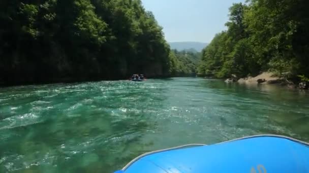 Grupo de turistas en un barco navegando a lo largo de un río de montaña Tara durante el rafting antes de rápidos extremos. Programa de entretenimiento Montenegro. Agua cristalina, hermoso paisaje natural con montañas — Vídeos de Stock