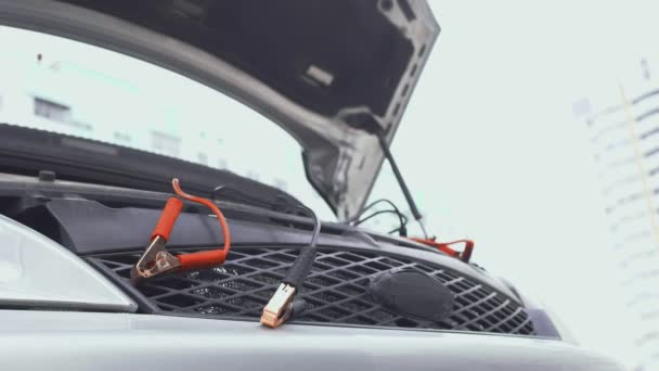 Antes de cargar la batería automotriz con cables de sujeción de puente positivos y negativos que los conectan a la terminal de correos. Capucha levantada en invierno durante el día en el aparcamiento. Problema de mal funcionamiento con auto. Parte 6 — Vídeo de stock