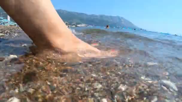 O mar lava os pés de uma menina na praia. Praia de seixos, relaxamento e venda, espaço de cópia, timelapse — Vídeo de Stock