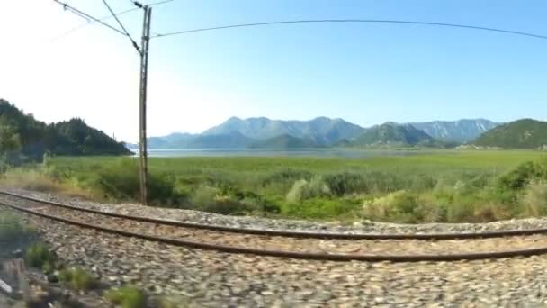 La vue depuis la fenêtre du bus sur les beaux paysages du Monténégro, les montagnes et parallèlement au chemin de fer, arrière-plan, ralenti — Video