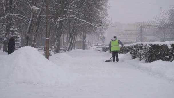 Le concierge enlève la neige en ville, la tempête de neige, les chutes de neige, le ralenti, le gilet BOBRUISK, BELARUS - LE 14 JANVIER 2019 — Video