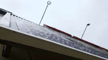 Trivision Billboard 'un istifleme sahnesinin düşük açılı çekimi. Büyük bir açık hava reklam yapısı. Üç mesaj işareti. Prizmalar her yeni reklam ve bilgi iletisini göstererek döner