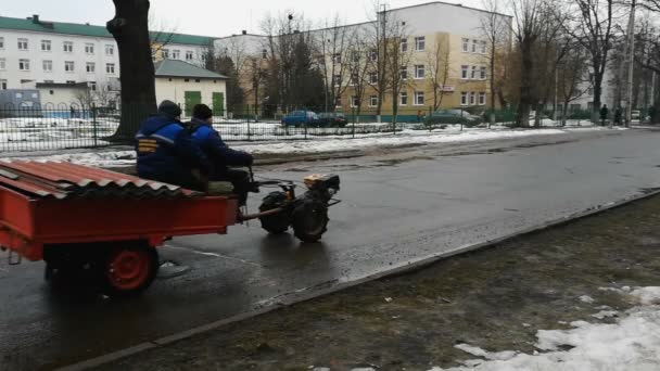 Människor i uniform rider på en konstig tvåhjulig fordon med en släpvagn på vintern på våt vägyta. Samhällstjänstemän, bostadsavdelningen. mulet väder — Stockvideo