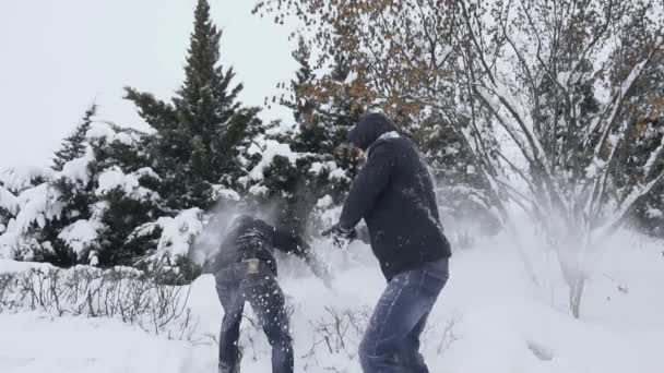 A srácok havat dobálnak egymásra télen, nappal, lassított felvételen. A férfiak szórakoznak és hülyéskednek. Szórakozás és gondtalan idő. Mentesség és egészség. — Stock videók