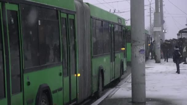 Public transport buses arrive at the bus stop during winter snowfall in MINSK, BELARUS 01.18.19. Cold and bad weather, blizzard. Danger of falling and risk of injuring on slippery roads in daytime — Stock Video