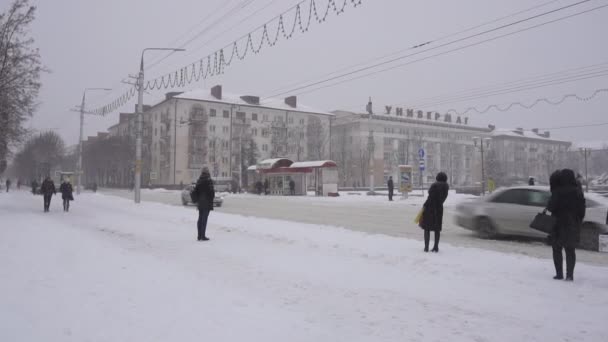 BOBRUISK, BELARUS - 14 DE ENERO DE 2019: La gente en la ciudad está esperando en la parada de autobús para el transporte, está nevando en la calle, el invierno — Vídeos de Stock