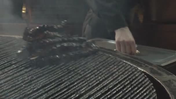 Процесс жарки свиных рёбер на гриле в ресторанном музее, традиционное блюдо, 4К. Ребра вращаются на гриле, процесс жарки — стоковое видео