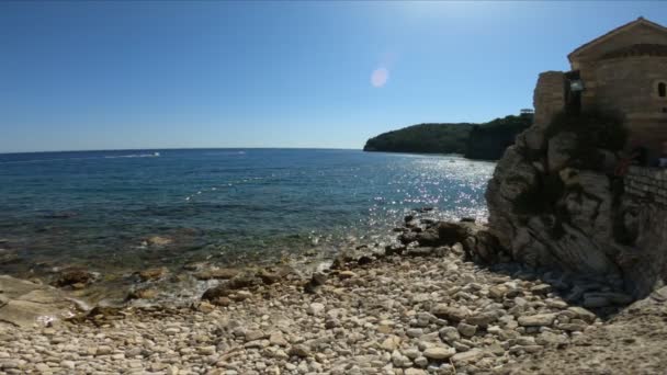 Bellissimo mare blu verdastro con una riva rocciosa contro un cielo blu. Il concetto di relax e relax in estate, natura bellissima. Rallentatore, turismo — Video Stock