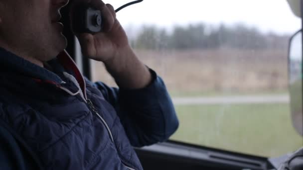 Een vrachtwagenchauffeur vraagt naar de verkeerssituatie van andere chauffeurs op de walkietalkie in de cabine. Het concept van communicatie-drivers op de weg op het luchtkanaal — Stockvideo