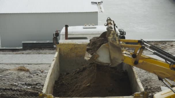 Graafmachine giet zand in een shell lichaam van Dump vrachtwagen voertuig tijdens een gebouw. Uitzicht vanaf het bovenste schot. Technische multifunctionele machine — Stockvideo