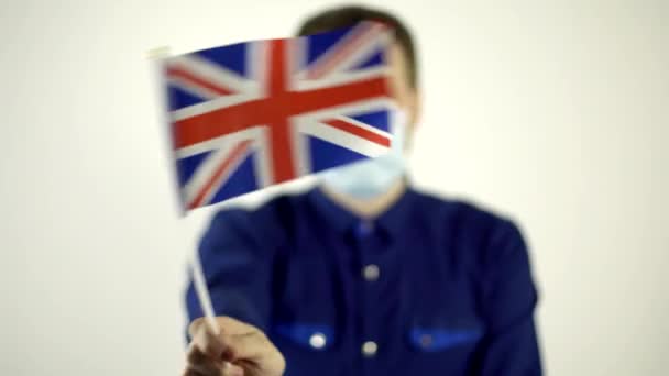 En man i skyddsmask mot viruset som viftar med det brittiska landets flagga. Country Coronavirus Disease Concept, COVID-2019, pandemi — Stockvideo