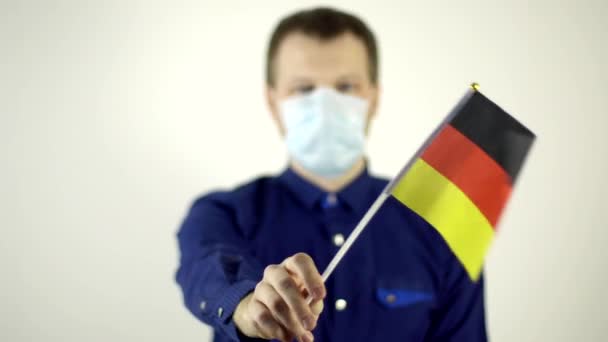 Ένας άνδρας με προστατευτική μάσκα στο πρόσωπό του ενάντια στον ιό που κυματίζει τη σημαία της Γερμανίας. Country Coronavirus Disease Concept, COVID-2019, πανδημία — Αρχείο Βίντεο