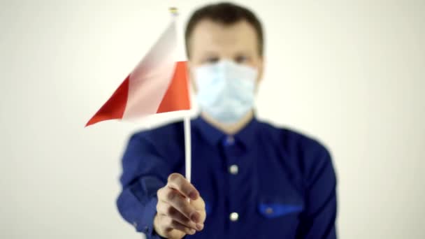 Человек в защитной маске на лице против вируса, размахивающего флагом страны Польша. Распространение коронавируса в стране, COVID-2019, пандемия — стоковое видео