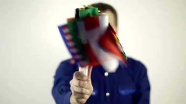 Virüse karşı koruyucu maskeli bir adam dünya ülkelerinin bayrağını sallıyor. Ülke Koronavirüs Hastalığı Konsepti, COVID-2019, salgın hastalık