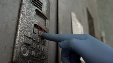 Bir adam tıbbi eldivenlerle dahili telefonun düğmelerine basıyor. Bakteri ve koronavirüse karşı koruma kavramı, salgın hastalık. COVID-19 'dan el koruması