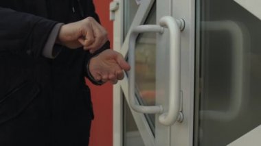 Bir adam dükkanın girişinde ellerini antiseptikle dezenfekte ediyor. Bir adam giriş kapısının koluna dokunur ve ellerini dezenfekte eder. Enfeksiyon ve koronovirüse karşı koruma kavramı