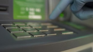 Tıbbi koruyucu eldivenlerle para çekmek için ATM 'de düğmelere basan bir adam. Koronavirüs salgını sırasında koruma ve güvenlik kavramı, COVID-19, karantina