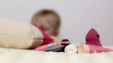 Küçük bir kız, yüzü için makyaj malzemeleri ve annesinin makyaj çantasından kadın pedleri yayıyor. Kadınlar için contalar.