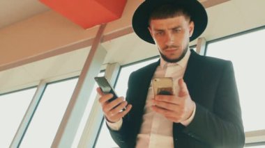 Siyah takım elbiseli ve şapkalı elinde iki akıllı telefon olan adam kendi kararlarını kendi verir. Yahudi ya da İtalyan mafyasına benziyor. Düşük açı, alt görüş. Sakallı ve bıyıklı bir iş adamı.