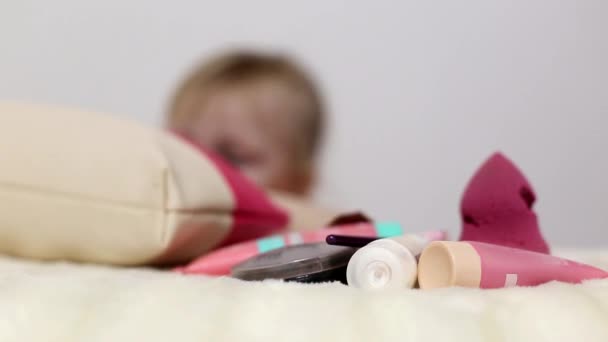 Маленькая девочка распространяет косметику для лица и женских подушечек из косметической сумки матери, прокладки для женщин — стоковое видео